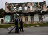 A couple wheel suitcases as they walk in front of a destroyed building in Izyum, Kharkiv Region, eastern Ukraine, amid the Russian invasion of Ukraine.