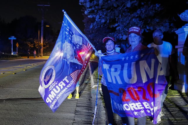 Supporters of former President Donald Trump hold flags in front of his home at Mar-A-Lago on August 8, 2022 in Palm Beach, Florida. The FBI raided the home to retrieve classified White House documents.
