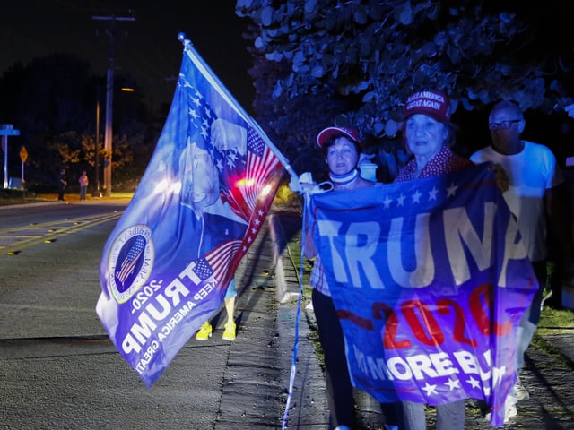 Supporters of former President Donald Trump hold flags in front of his home at Mar-A-Lago on August 8, 2022 in Palm Beach, Florida. The FBI raided the home to retrieve classified White House documents.