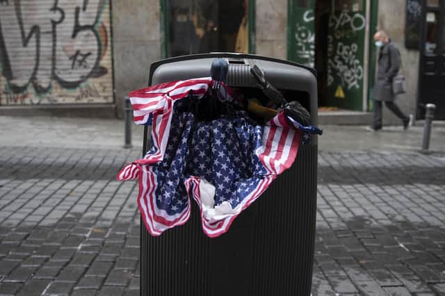 An umbrella in the colours of the US flag lies stuffed in a trash bin in Madrid, Spain. Picture: AP Photo/Paul White