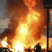 Staff extinguish flames from Haas driver Romain Grosjean of France's car after a crash during the Formula One race in Bahrain International Circuit in Sakhir, Bahrain, Sunday, Nov. 29, 2020. (Brynn Lennon, Pool via AP)