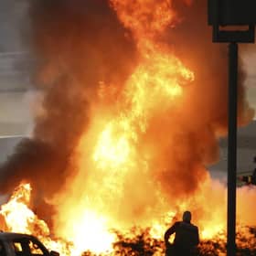 Staff extinguish flames from Haas driver Romain Grosjean of France's car after a crash during the Formula One race in Bahrain International Circuit in Sakhir, Bahrain, Sunday, Nov. 29, 2020. (Brynn Lennon, Pool via AP)