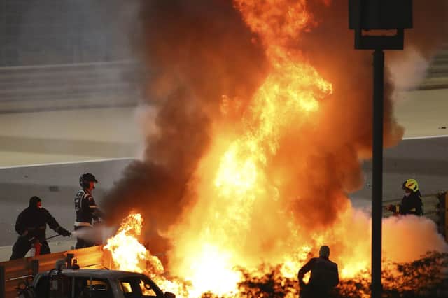 Staff extinguish flames from Haas driver Romain Grosjean of France's car after a crash during the Formula One race in Bahrain International Circuit in Sakhir, Bahrain, Sunday, Nov. 29, 2020. (Brynn Lennon, Pool via AP)