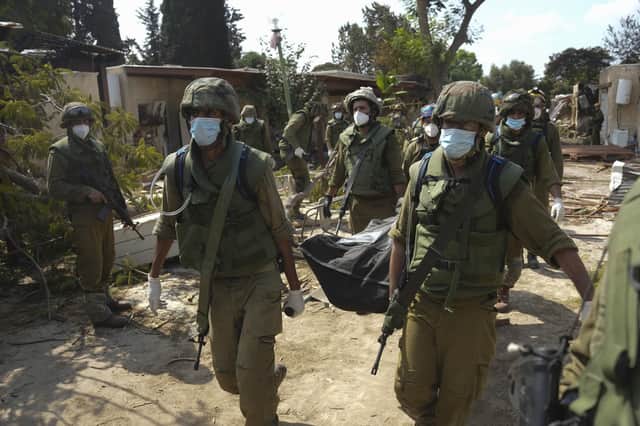 Israeli soldiers carry a body of a person killed in Hamas attack in kibbutz Kfar Azza. Photo: AP Photo/Erik Marmor