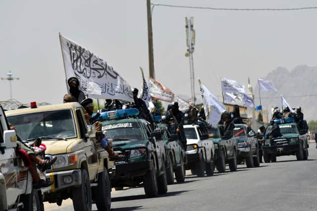 Taliban fighters wave flags in a parade to celebrate regaining control of Afghanistan following the withdrawal of US troops