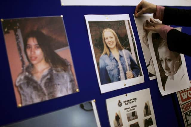 A police officer pins up photographs of five women murdered while working as prostitutes on a board at Suffolk Police headquarters during the hunt for their killer (Picture: Bruno Vincent/Getty Images)