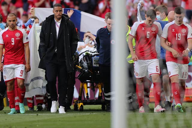 Denmark's players escort Eriksen off the pitch - with the player now conscious on the stretcher.