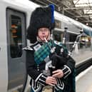 Border Piper Sandy Mutch beside the train at Edinburgh Waverley Station. Picture: TransPennine Express