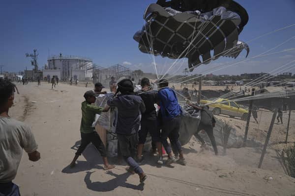 Palestinians rush to collect humanitarian aid airdropped by parachutes into Deir al-Balah, central Gaza Strip, Tuesday, Aug. 5, 2025. (AP Photo/Abdel Kareem Hana)