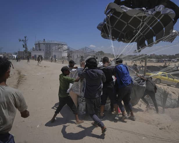 Palestinians rush to collect humanitarian aid airdropped by parachutes into Deir al-Balah, central Gaza Strip, Tuesday, Aug. 5, 2025. (AP Photo/Abdel Kareem Hana)