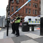 Police, alongside a floral tribute, at the scene in West George Street, Glasgow, after Badreddin Abadlla Adam, 28, from Sudan, was shot dead by police