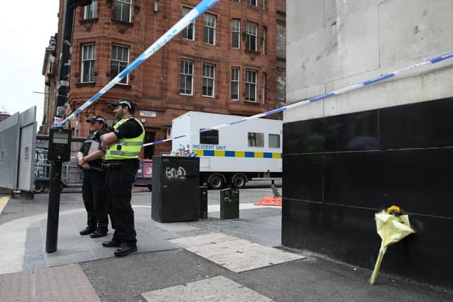 Police, alongside a floral tribute, at the scene in West George Street, Glasgow, after Badreddin Abadlla Adam, 28, from Sudan, was shot dead by police