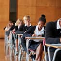 Teenage Students In Uniform Sitting Examination In School Hall