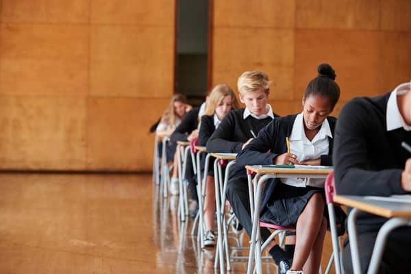 Teenage Students In Uniform Sitting Examination In School Hall