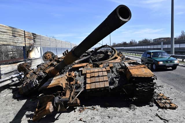 A car drives past a burnt-out Russian tank on a road west of Kyiv (Picture: Genya Savilov/AFP via Getty Images)