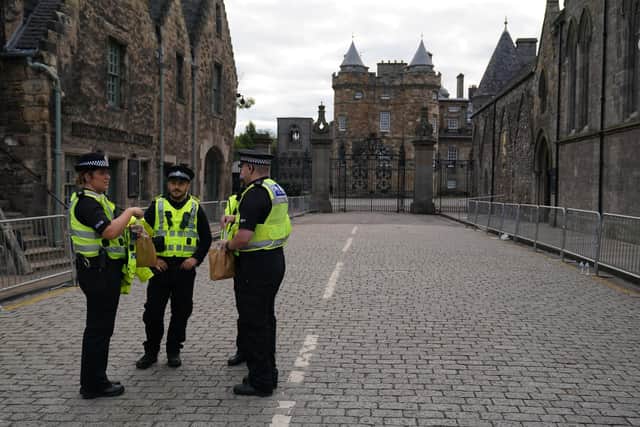 Police officers outside the gates of the Palace of Holyroodhouse in Edinburgh. Queen Elizabeth II's coffin will be transported on a six-hour journey from Balmoral to the Palace of Holyroodhouse in Edinburgh, where it will lie at rest. Picture date: Sunday September 11, 2022.