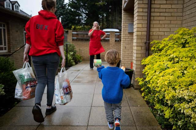 A child helps a member of staff to carry food donations.