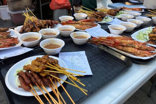 Chicken skewers and prawns being cooked on a barbecue in Satay Street. Pic: Hannah Stephenson/PA.