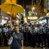 A pro-democracy activist holds a yellow umbrella in front of a police line in Hong Kong (Picture: Chris McGrath/Getty Images)