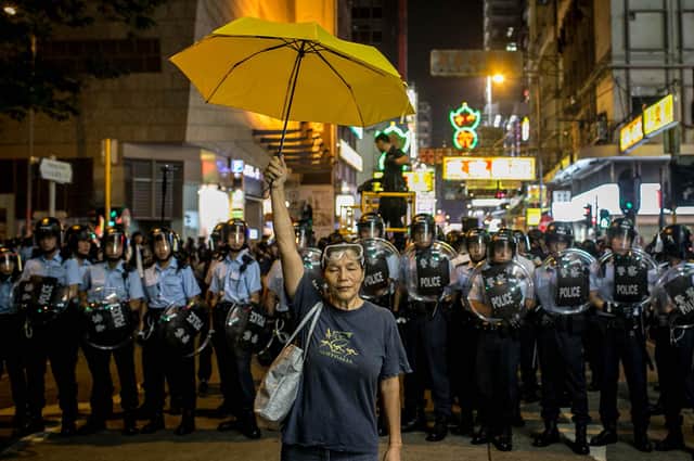 A pro-democracy activist holds a yellow umbrella in front of a police line in Hong Kong (Picture: Chris McGrath/Getty Images)