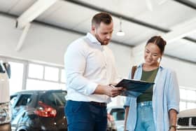 A car buyer discusses finance options with a dealership representative. New research suggests many UK drivers now regret the car finance deals they agreed to in the past decade.