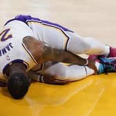 Los Angeles Lakers forward LeBron James holds his ankle after going down with an injury during the first half of the game against the Atlanta Hawks. Picture: Marcio Jose Sanchez/AP