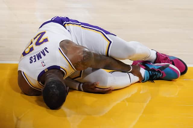 Los Angeles Lakers forward LeBron James holds his ankle after going down with an injury during the first half of the game against the Atlanta Hawks. Picture: Marcio Jose Sanchez/AP