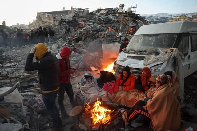 Survivors gather next to a bonfire outside collapsed buildings in Kahramanmaras on February 8, 2023, after their homes were destroyed in a 7.8 magnitude earthquake which struck the border region of Turkey and Syria on February 6. The sprawling scale of the disaster that flattened thousands of buildings, trapping an unknown number of people, has swamped relief operations already hampered by freezing weather. (Photo by Adem ALTAN / AFP) (Photo by ADEM ALTAN/AFP via Getty Images)