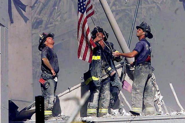 Firefighters raise a flag late in the afternoon on Tuesday, Sept. 11, 2001, in the wreckage of the World Trade Center towers in New York. In the most devastating terrorist onslaught ever waged against the United States, knife-wielding hijackers crashed two airliners into the World Trade Center on Tuesday, toppling its twin 110-story towers. (AP Photo/The Record, Thomas E. Franklin)Terrorist attacks in America 11.09.2001.