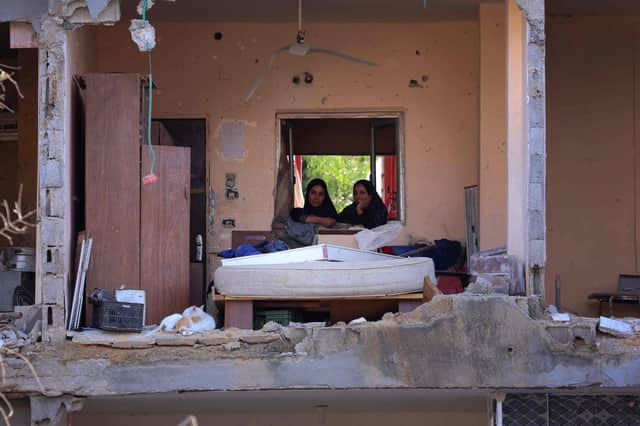 Palestinian women sit in a multi-storey building after a wall collapsed when it was hit by an Israeli airstrike (Picture: Emmanuel Dunand/AFP via Getty Images)