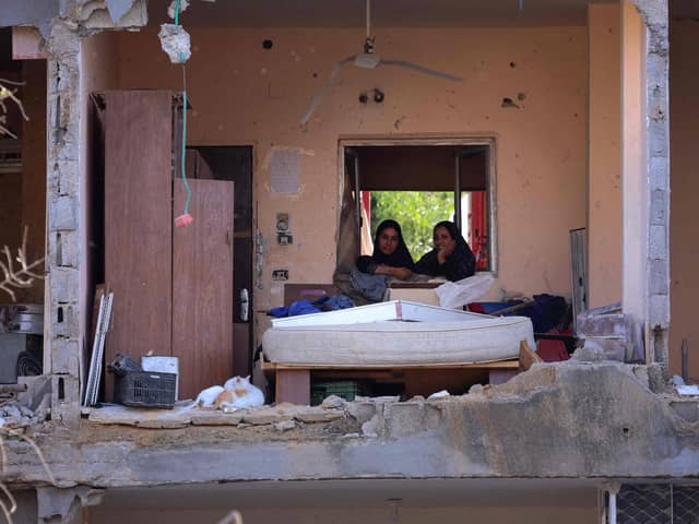 Palestinian women sit in a multi-storey building after a wall collapsed when it was hit by an Israeli airstrike (Picture: Emmanuel Dunand/AFP via Getty Images)