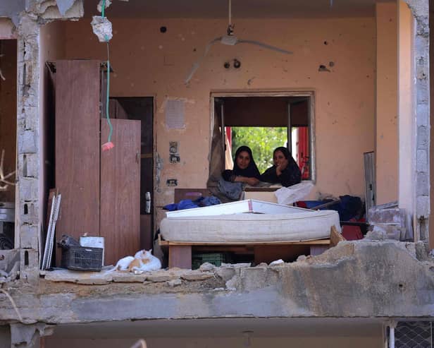 Palestinian women sit in a multi-storey building after a wall collapsed when it was hit by an Israeli airstrike (Picture: Emmanuel Dunand/AFP via Getty Images)