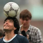 Diego Maradona balances a ball on his head as he walks off the Argentina training pitch in 1986.