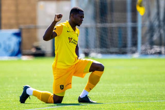 Livingston midfielder Marvin Bartley supports football's anti-racism movement by taking a knee ahead of a match this season. Photo by Ross MacDonald / SNS Group