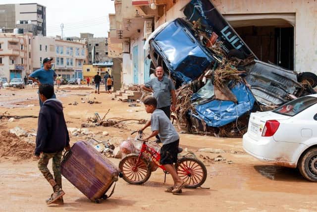 A boy pulls a suitcase past debris in a flash-flood damaged area in Derna, eastern Libya.