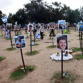 People walk past portraits of people taken captive or killed by Hamas militants during the October 7 attacks, during a visit at the site where the Supernova music festival took place near Kibbutz Reim in southern Israel.