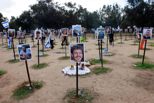 People walk past portraits of people taken captive or killed by Hamas militants during the October 7 attacks, during a visit at the site where the Supernova music festival took place near Kibbutz Reim in southern Israel.