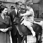 Prince Charles sitting on a statue watched by Princess Elizabeth, the Duke of Edinburgh, Princess Margaret and Queen Elizabeth while on holiday at Balmoral in August 1951.