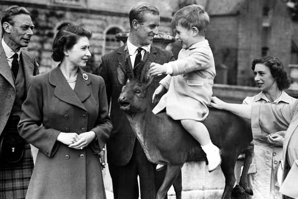 Prince Charles sitting on a statue watched by Princess Elizabeth, the Duke of Edinburgh, Princess Margaret and Queen Elizabeth while on holiday at Balmoral in August 1951.
