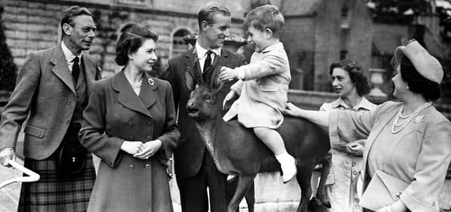 Prince Charles sitting on a statue watched by Princess Elizabeth, the Duke of Edinburgh, Princess Margaret and Queen Elizabeth while on holiday at Balmoral in August 1951.