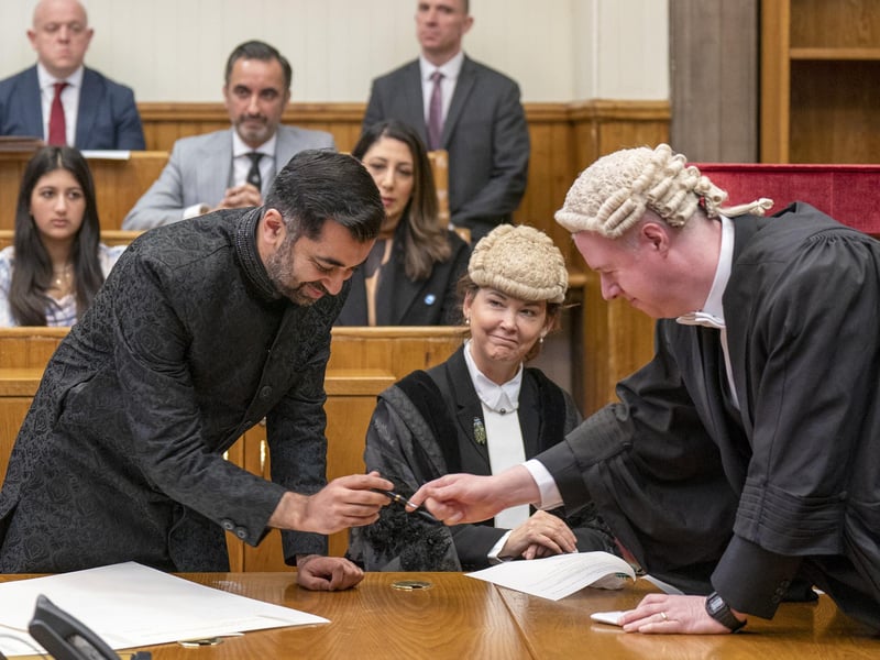 Humza Yousaf signs the parchments as he is sworn in as First Minister of Scotland at the Court of Session