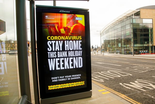 A sign at a bus stop outside John Lewis warns the public to stay at home.