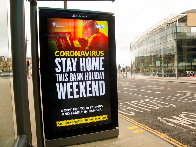 A sign at a bus stop outside John Lewis warns the public to stay at home.