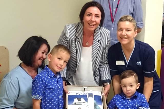 Mum-of-two Lisa Quarrell visited the Royal Hospital for Sick Children (RSHC) in Edinburgh last week to donate a state-of-the-art vein finder device to help children who, like her own son Cole, have a fear of needles.
l to r: “Play Specialist Margaret McEwan, Lisa’s son Dylan, Lisa Quarrell, Dr Anthony Wiggins, Ward Manager Karen Duguid and Cole presenting the equipment in Ward 7 of the RHSC in Edinburgh.”