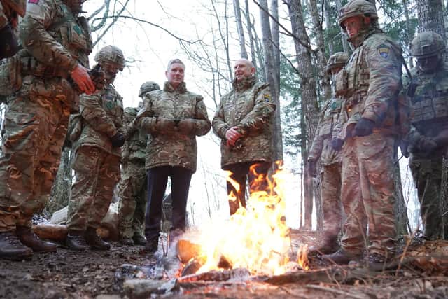 Labour leader Sir Keir Starmer (fourth from left) and shadow defence secretary John Healey (fifth from left) standing behind a fire during their visit to meet British troops at a Nato base in Tapa in Estonia. Picture: Stefan Rousseau/PA Wire