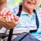 A nurse holds the hand of an older woman