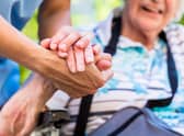 A nurse holds the hand of an older woman