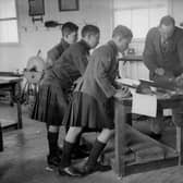 A group of boys watch a woodwork teacher planing a length of wood at the Queen Victoria School, Dunblane, Perthshire in 1931 (Picture: Fox Photos/Getty Images)