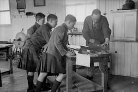 A group of boys watch a woodwork teacher planing a length of wood at the Queen Victoria School, Dunblane, Perthshire in 1931 (Picture: Fox Photos/Getty Images)
