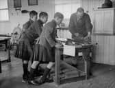 A group of boys watch a woodwork teacher planing a length of wood at the Queen Victoria School, Dunblane, Perthshire in 1931 (Picture: Fox Photos/Getty Images)